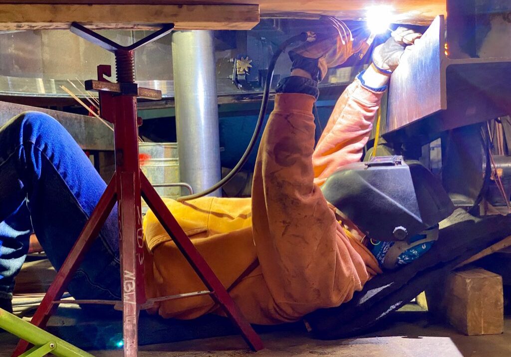 A worker welding underneath a unit. NBW Inc.